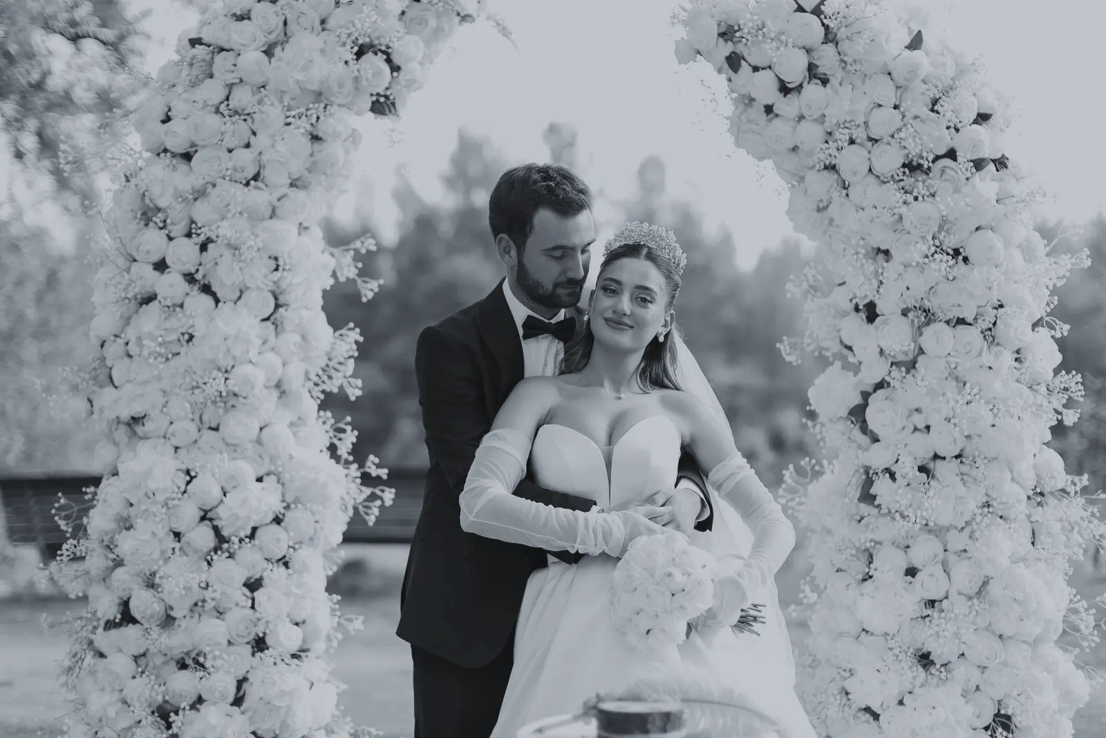 Couple in front of a white rose arch, unedited