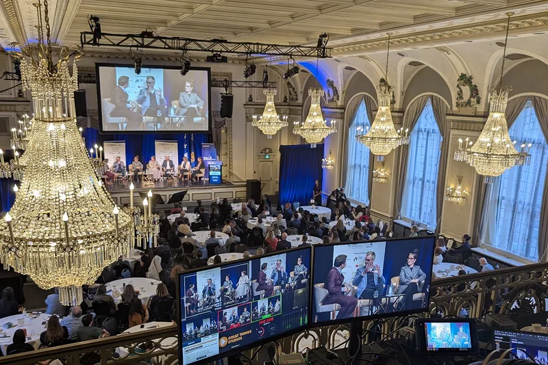 A multi-camera video production setup at a conference hall with monitors in the foreground