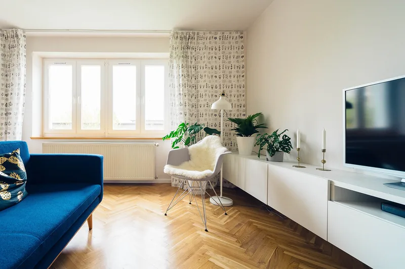A bright living room with a blue sofa and herringbone floor
